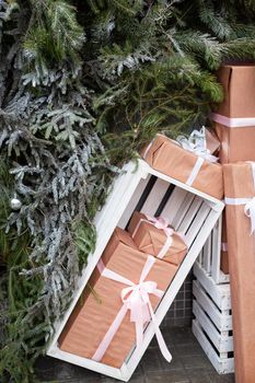 Craft gift boxes outside against the Christmas tree wall. The concept of gifts for the New Year and Christmas