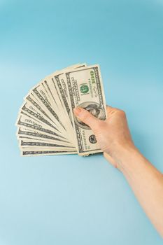 Female hands holding 100 dollar bills isolated on blue background