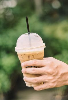 Hand hold iced latte coffee in a glass. cold summer drink background