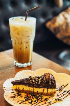 A slide of chocolate cake with iced latte coffee in a  tall glass. cold summer drink background