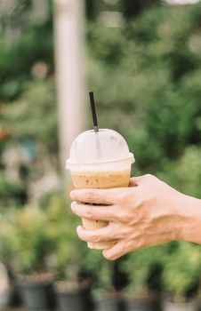 Hand hold iced latte coffee in a glass. cold summer drink background