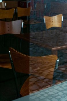 Wooden chairs and tables behind the glass wall of a closed bar