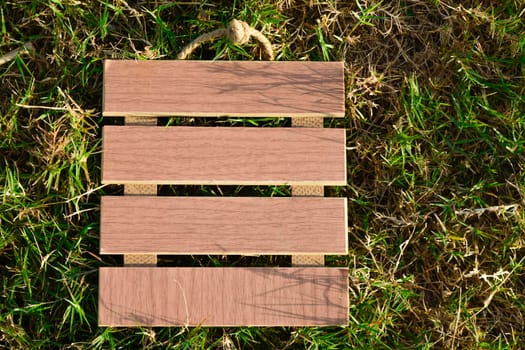 View of empty wooden frame laying on green grass background. Copy space. Flat Lay.