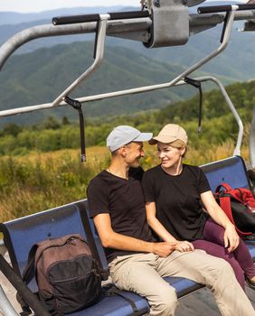 People sit on the ski elevator. View from the back. Summer, green forest. summer family vacation in the mountains