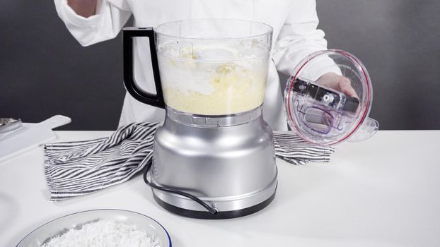 Mixing ingredients in a food processor to prepare homemade coconut cookies.