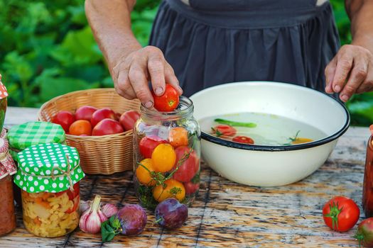 Senior woman preserving vegetables in jars. Selective focus. Food.