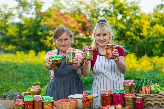 Women with jar preserved vegetables for the winter mother and daughter. Selective focus. Food.