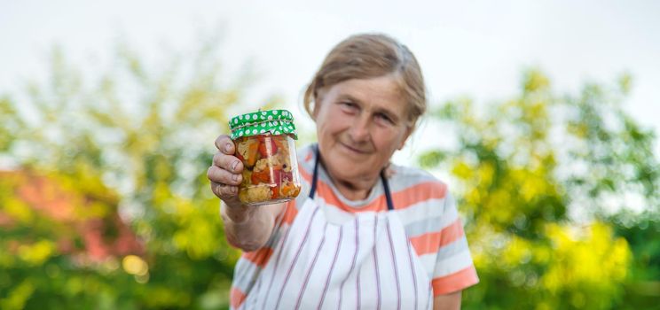 Senior woman preserving vegetables in jars. Selective focus. Food.