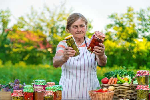 Senior woman preserving vegetables in jars. Selective focus. Food.