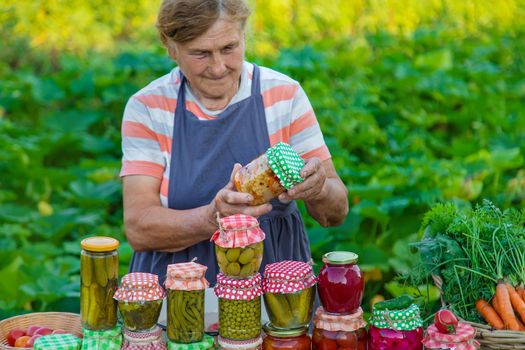 Senior woman preserving vegetables in jars. Selective focus. Food.