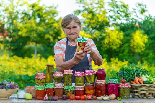 Senior woman preserving vegetables in jars. Selective focus. Food.