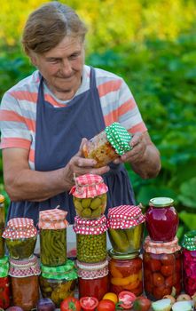 Senior woman preserving vegetables in jars. Selective focus. Food.