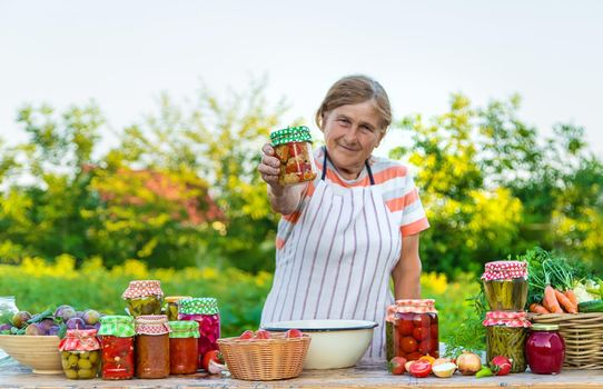 Senior woman preserving vegetables in jars. Selective focus. Food.