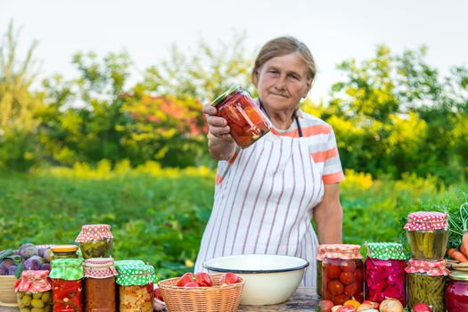 Senior woman preserving vegetables in jars. Selective focus. Food.