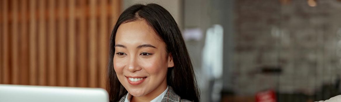 Close up of smiling asian business woman working laptop sitting in cozy office. High quality photo