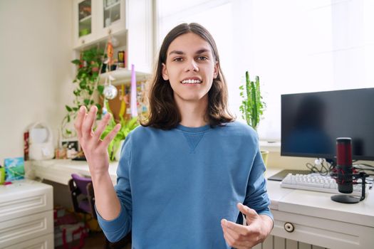 Handsome teenage male student talking looking at web camera. Teenager recording video look at webcam in home. Distance learning e-education freelancing youth technology