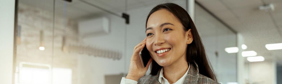 Asian business woman talking phone with client and smile. Blurred background