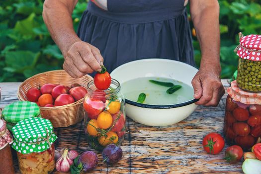 Senior woman preserving vegetables in jars. Selective focus. Food.