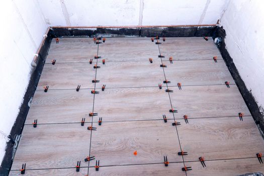 view of the bathroom floor during renovation with the tile alignment system that holds the tile in a given position. plastic clips and wedges. repair school. Industrial education