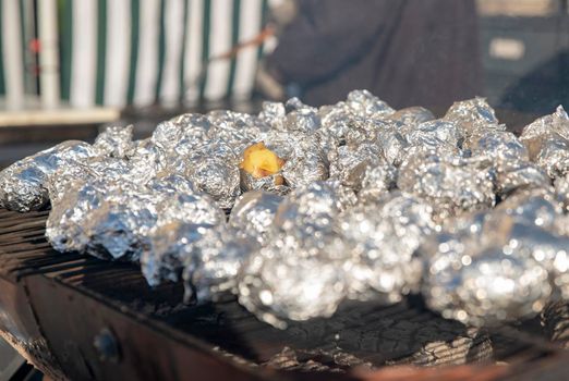 Many potatoes in foil on the barbecue