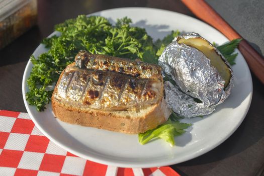 Herring grilled and baked in foil potatoes on a plate