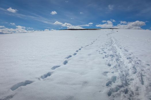 Snowcapped mountain with alpinist footprints in Jotunheimen, Norway, Scandinavia
