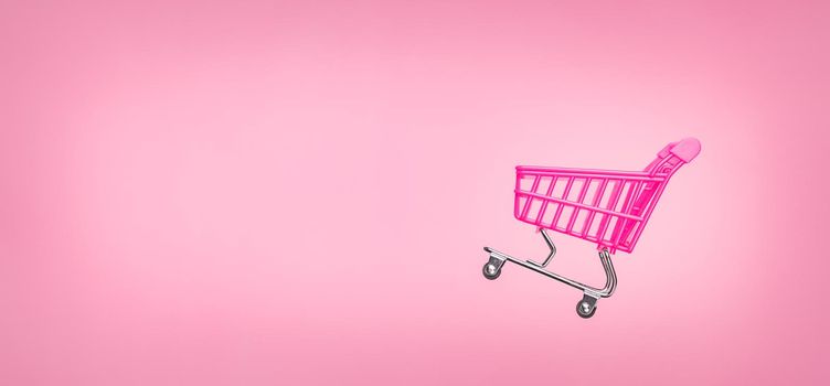 Empty trolley cart isolated pink background. Pink shopping trolley supermarket concept. Banner pink concept sales online shopping cart supermarket sales shopping symbol. Sale cart shop banner E online