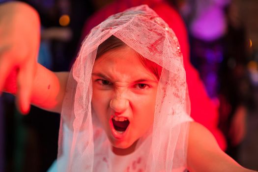 Close up portrait of screaming girl at a halloween party in weeding dress. Scary expression.