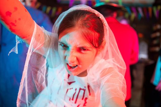 Portrait of beautiful zombie bridal looking creepy into the camera for halloween. Girl in weeding dress at halloween carnival.