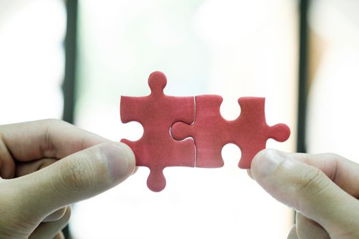 Close up of business people assemble jigsaw puzzle find perfect match, business solution, diverse employees put pieces together engaged in team building activity at work, teamwork, creative thinking concept.
