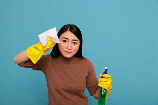Confidence asian housewife from day to day routine with tissue paper holding in the yellow glove and detergent spray, Cleaning home concept, Faithful serious female from chores