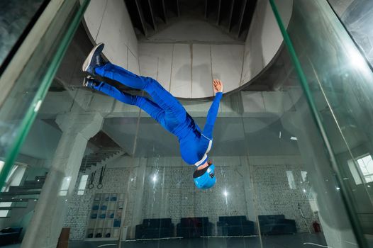 A man in overalls and a protective helmet enjoys flying in a wind tunnel. Free fall simulator.