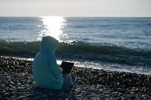 Caucasian woman working freelance on laptop on the beach