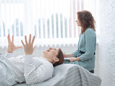 A middle-aged woman lies on a couch in a session with a psychoanalyst. Female patient in despair