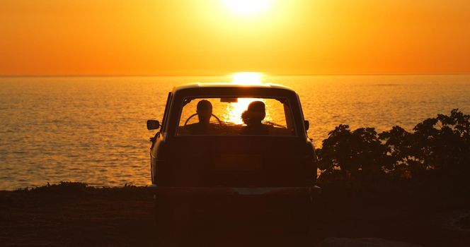 Forgetting the world for a while. Rearview shot of two unrecognizable girl friends sitting in a vehicle while on a road trip at the beach