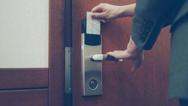 Close-up of businesswoman in suit open hotel room door using contactless key card and entering the room. Travel, business and people concept