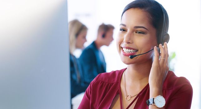 Customer service speaking. a cheerful young businesswoman wearing a headset while talking to a client over the phone inside of the office
