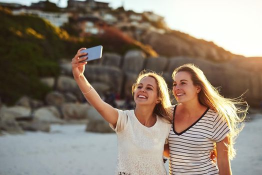 Selfies are a must. two friends taking a selfie while spending the day at the beach