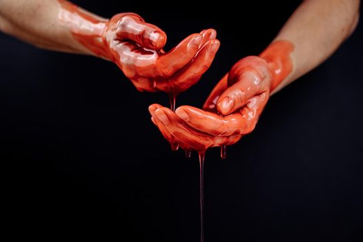 Women's hands in a viscous red liquid similar to blood