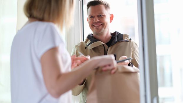 Smiling courier man delivers parcel to woman. Home delivery service concept