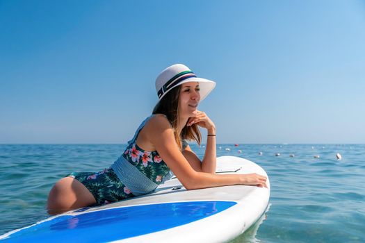 Happy young woman in swimsuits doing yoga on sup board in calm sea, early morning. Balanced pose - concept of healthy life and natural balance between body and mental development