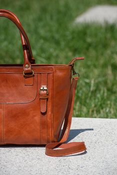 close-up part photo of luxury orange leather bag on a white marble. outdoors photo