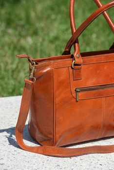 close-up part photo of luxury orange leather bag on a white marble. outdoors photo