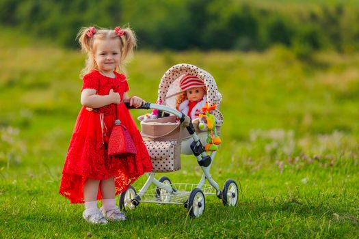 girl playing with a doll in a stroller in nature