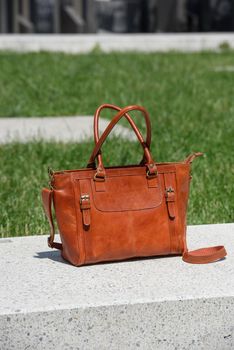 close-up photo of luxury orange leather bag on a white marble. outdoors photo