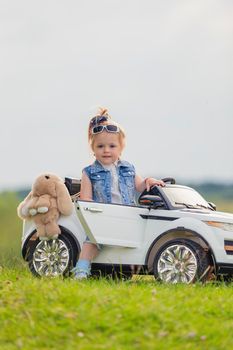 small child stands near his car on the lawn