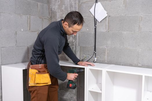 Young man assembling furniture in new house