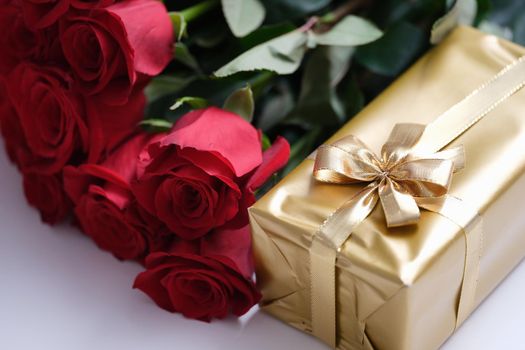 Red rose flowers and gift box on table. Women's day and birthday celebration concept