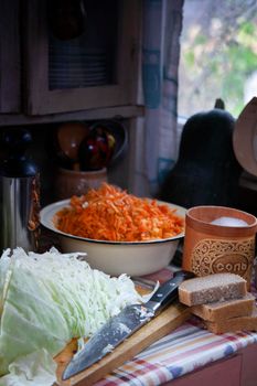 Cabbage sauerkraut praparation with ingredients - cut cabage, grated carrot, salt and rye bread in old farm kitchen, still life, selective focus.