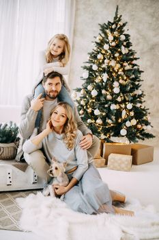 Happy family: mom, dad and pet. Family in a bright New Year's interior with a Christmas tree.